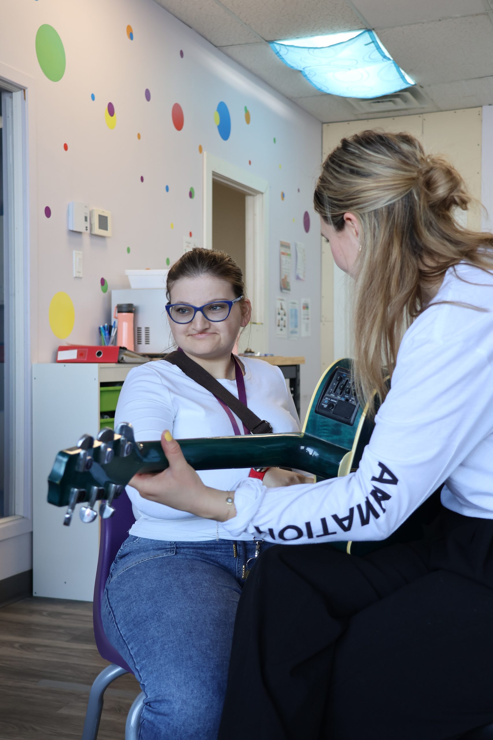 Animatrice Musicofolie jouant de la guitare au chevet d'une résidente