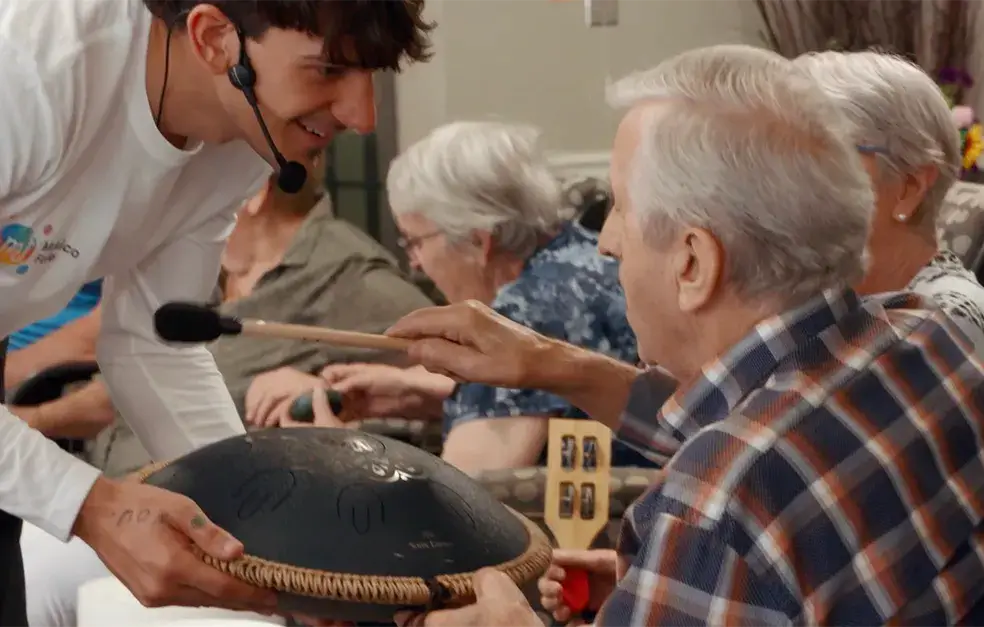 Un animateur de Musicofolie joue du handpan avec des aîné·e·s réunis dans un salon